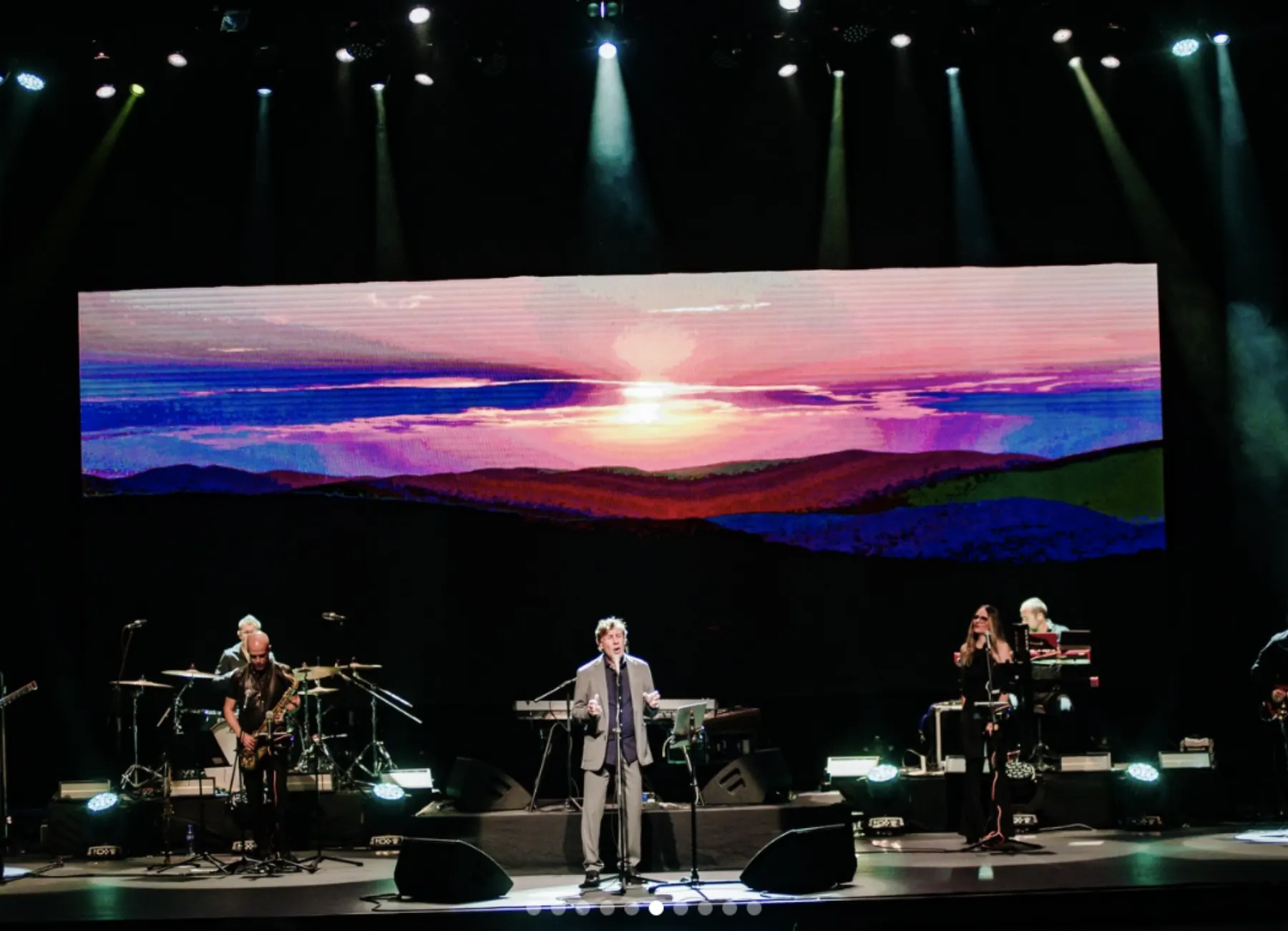 Palco com painel de luzes e banda durante apresentação